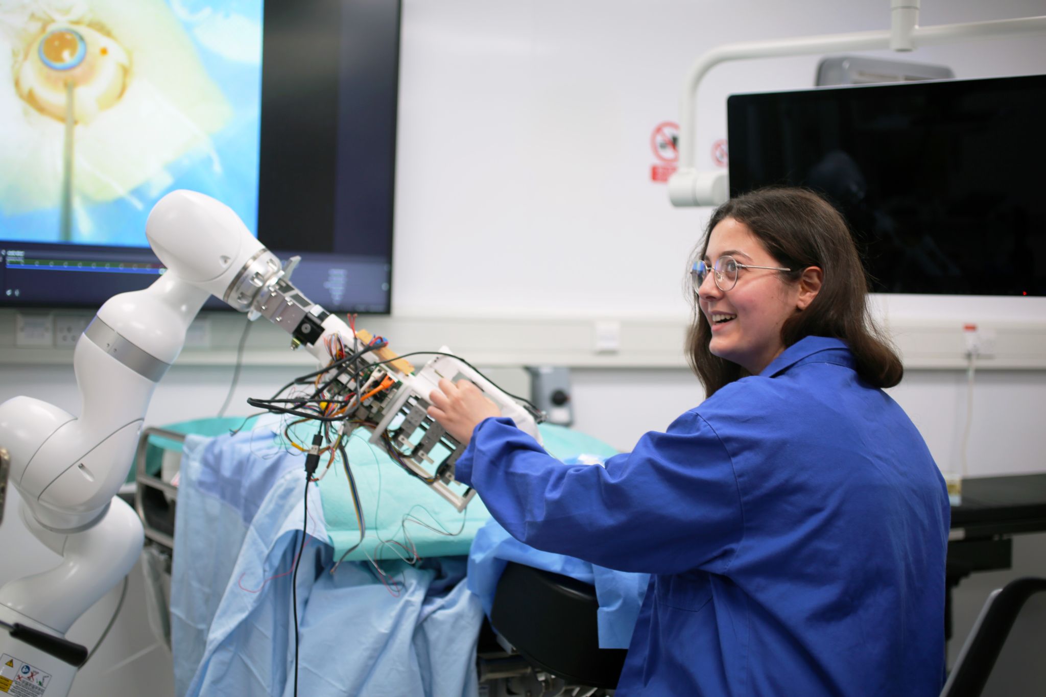 Adriana Namour in a blue lab coat working with a retinal microsurgery robot